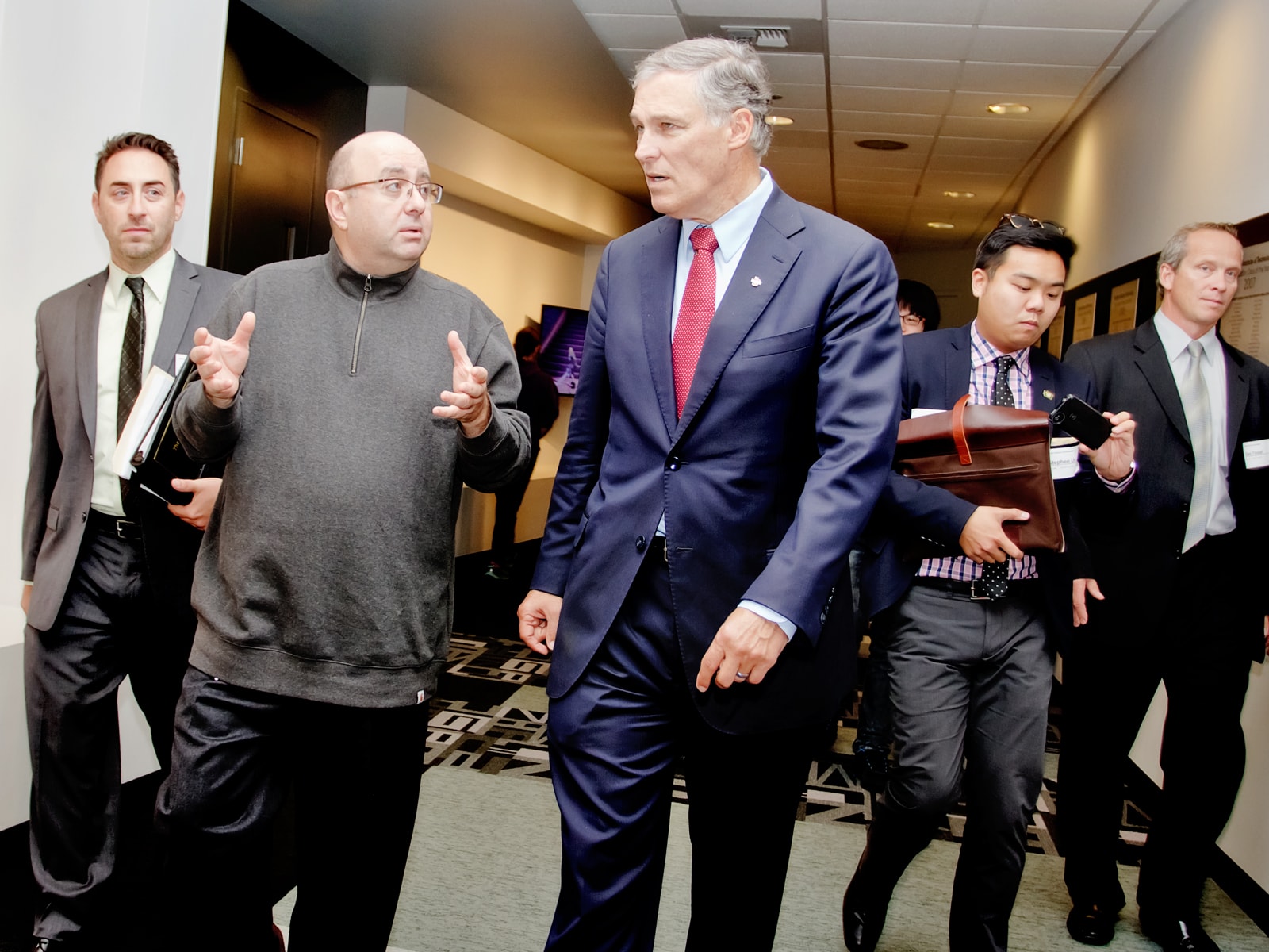 DigiPen founder Claude Comair and Washington Governor Jay Inslee walking down the hall surrounded by staffers
