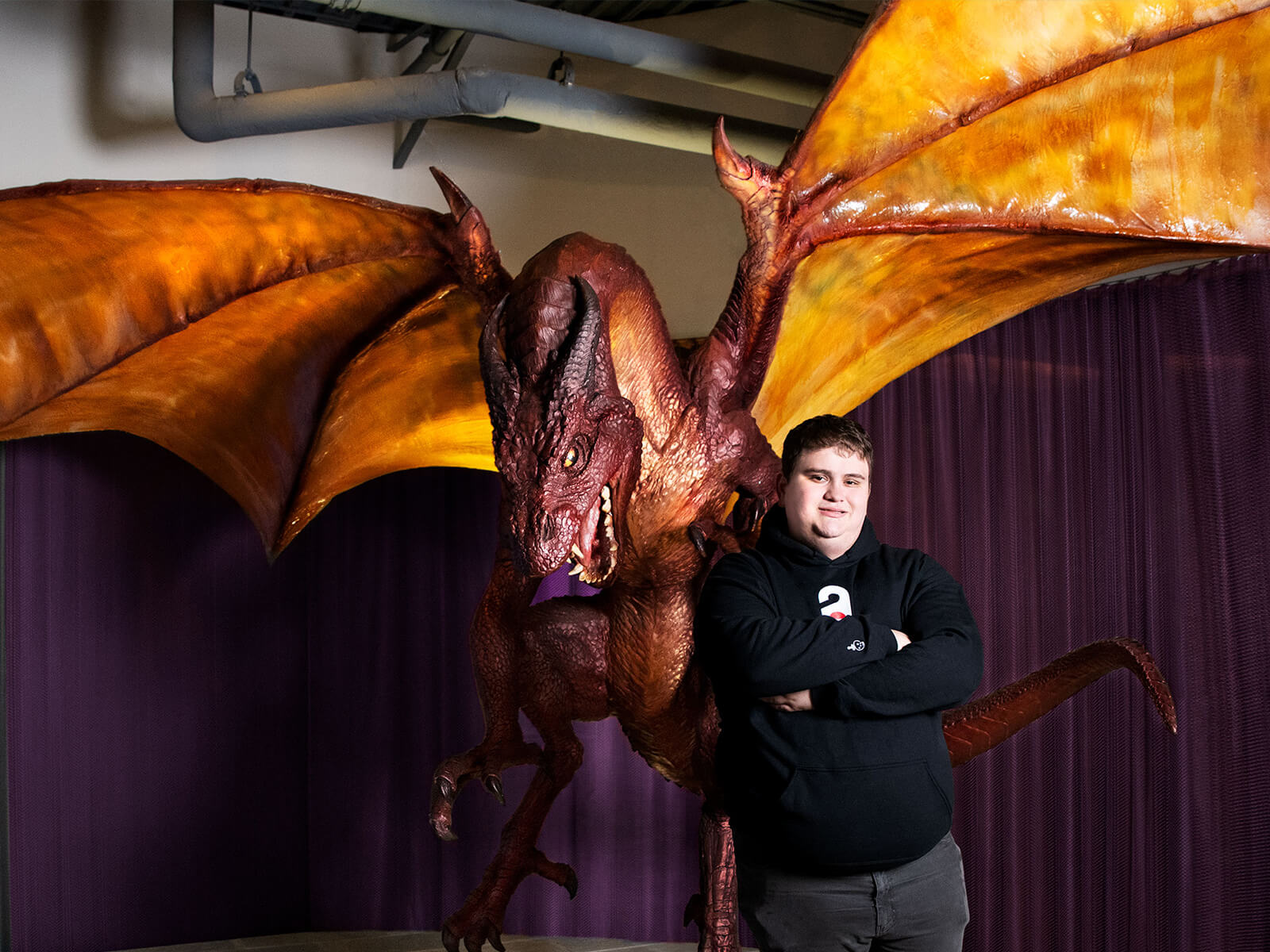 Kaan Palaz stands in front of a giant dragon statue at Wizards of the Coast headquarters.