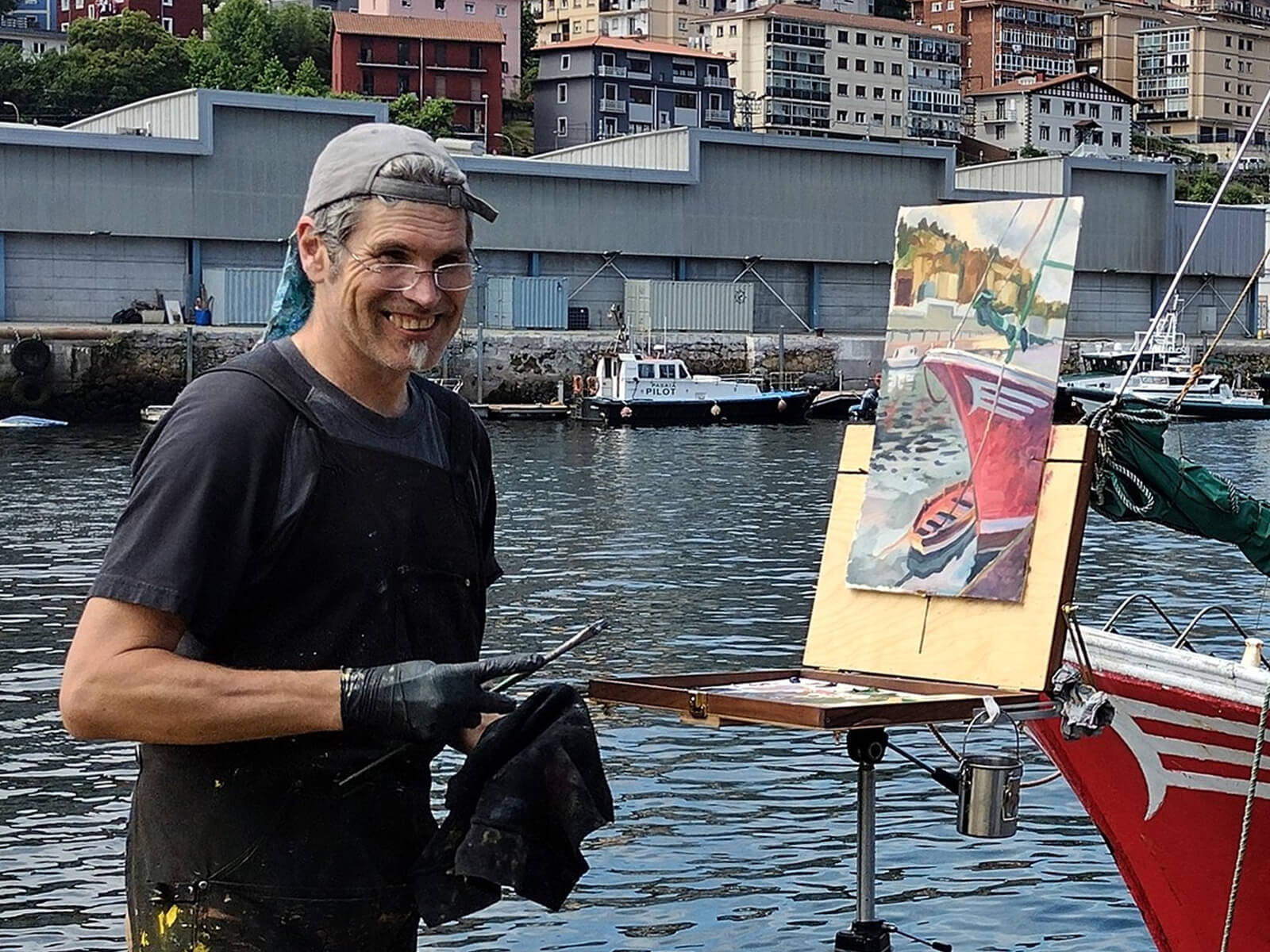 Steffon Moody stands and smiles as he paints the surrounding harbor and boat onto his canvas