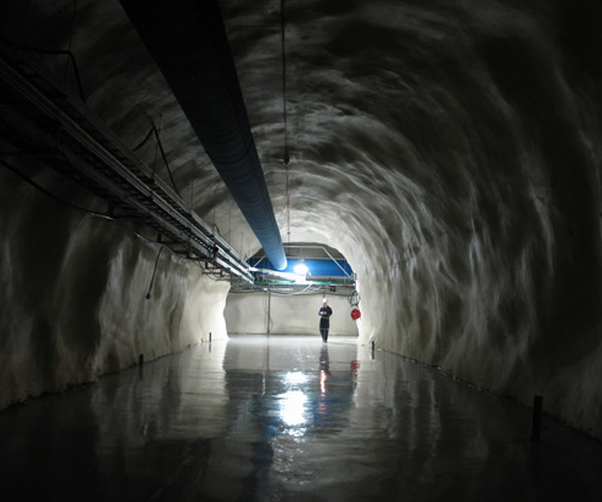 A worker standing in a dark, wet tunnel at SNOLAB