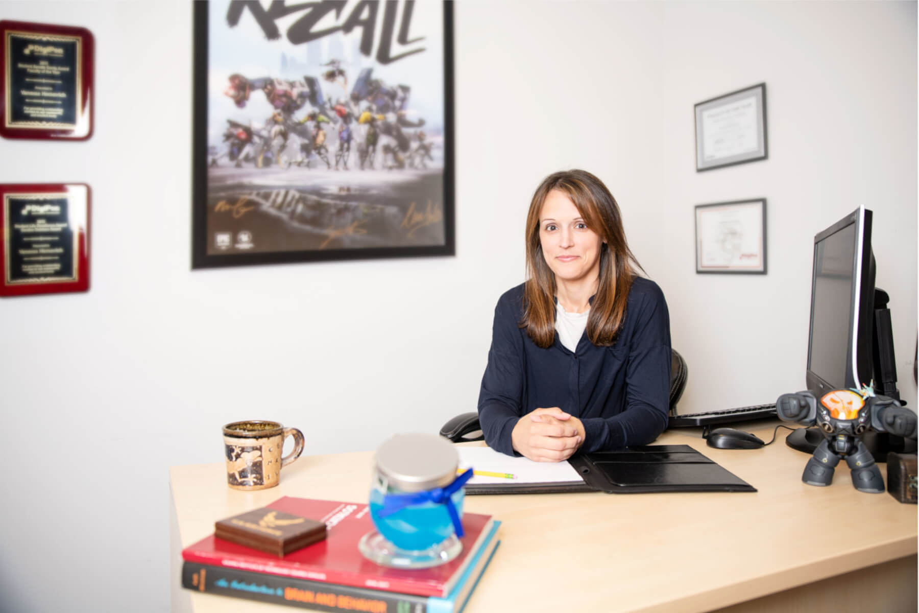 Professor Vanessa Hemovich poses at her desk in her office.