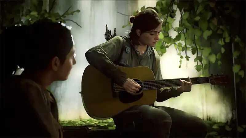 Ellie plays guitar as another woman watches.