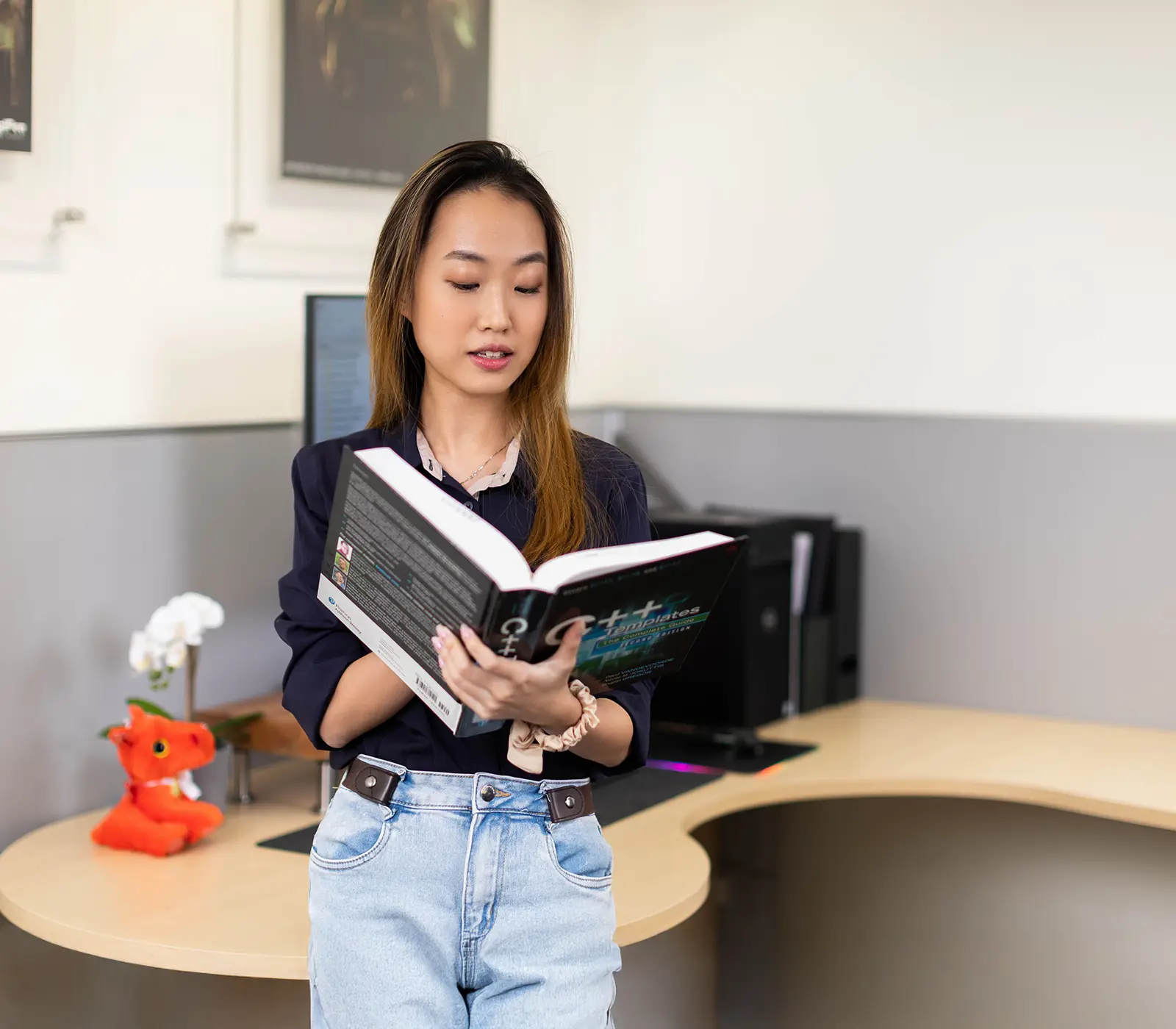 A DigiPen student stands reading a introductory book to C++.