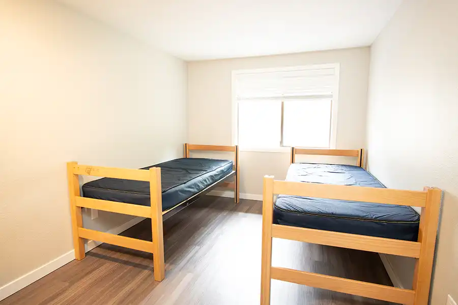 Two beds near a window in a bedroom.