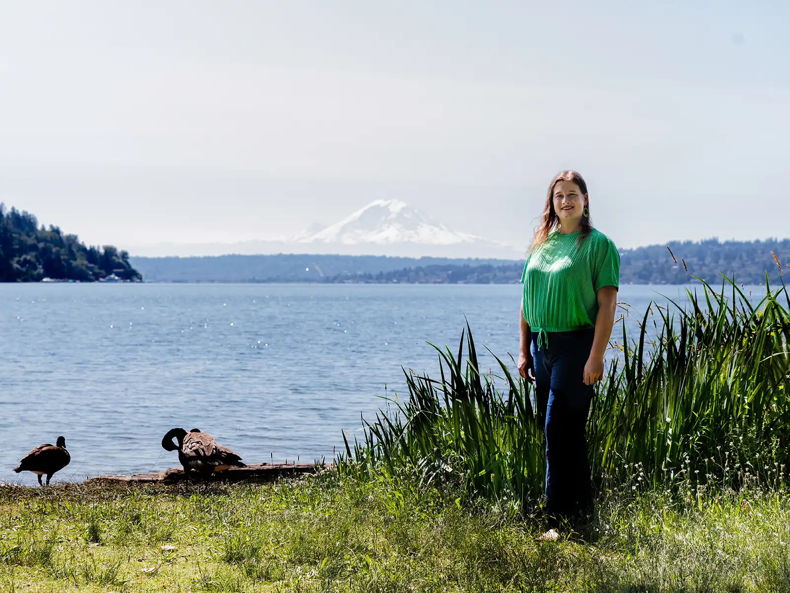 Autumn Palfenier stands on a lake shore with Mount Rainier visible in the distance.