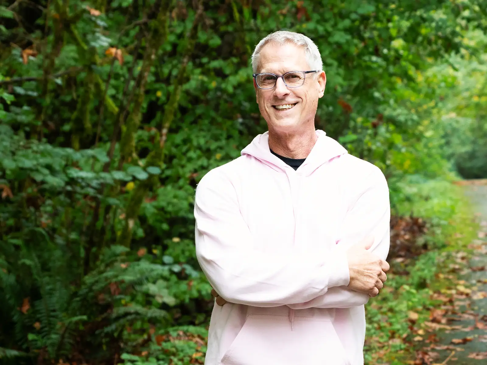 Matt Brunner poses with his arms crossed on a tree-lined trail.