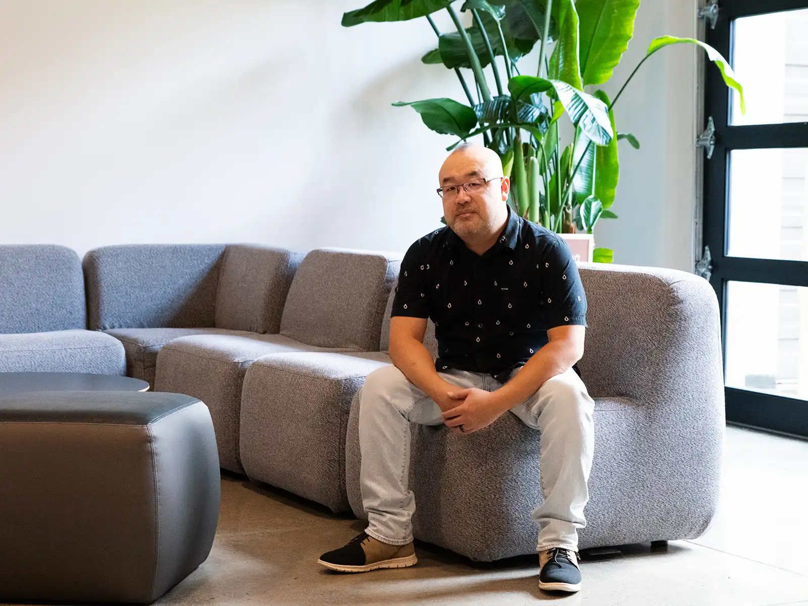 Randall Ng sits on a couch.