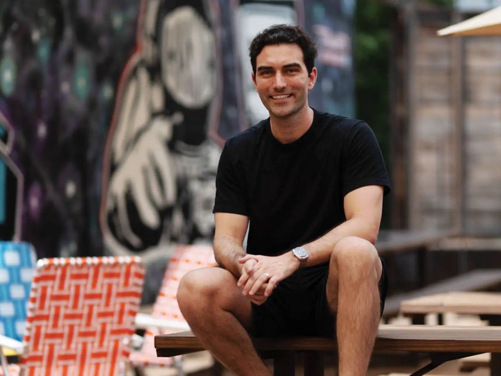 Adam Estella sits on an outdoor picnic table.