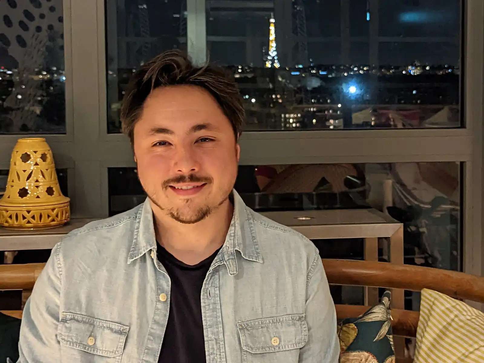 Eduardo Righi Chaves in Paris apartment with the Eifel Tower lit up in the distance.