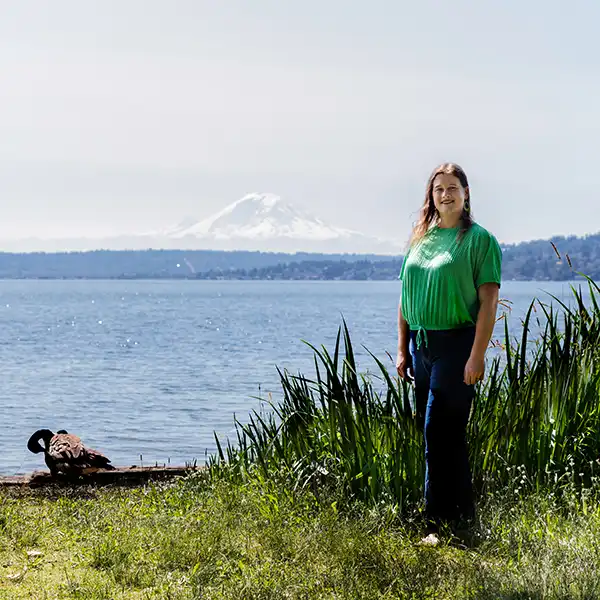 Autumn Palfenier stands on a lake shore with Mount Rainier visible in the distance.