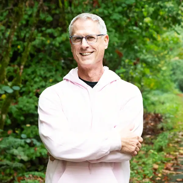 Matt Brunner poses with his arms crossed on a tree-lined trail.