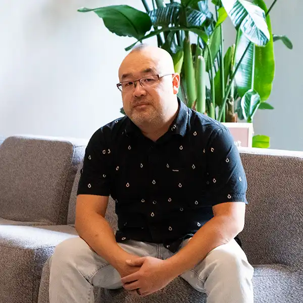 Randall Ng sits on a couch.