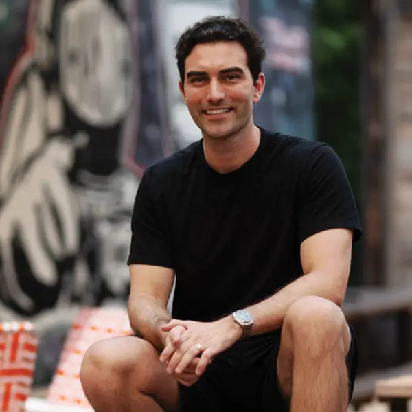 Adam Estella sits on an outdoor picnic table.