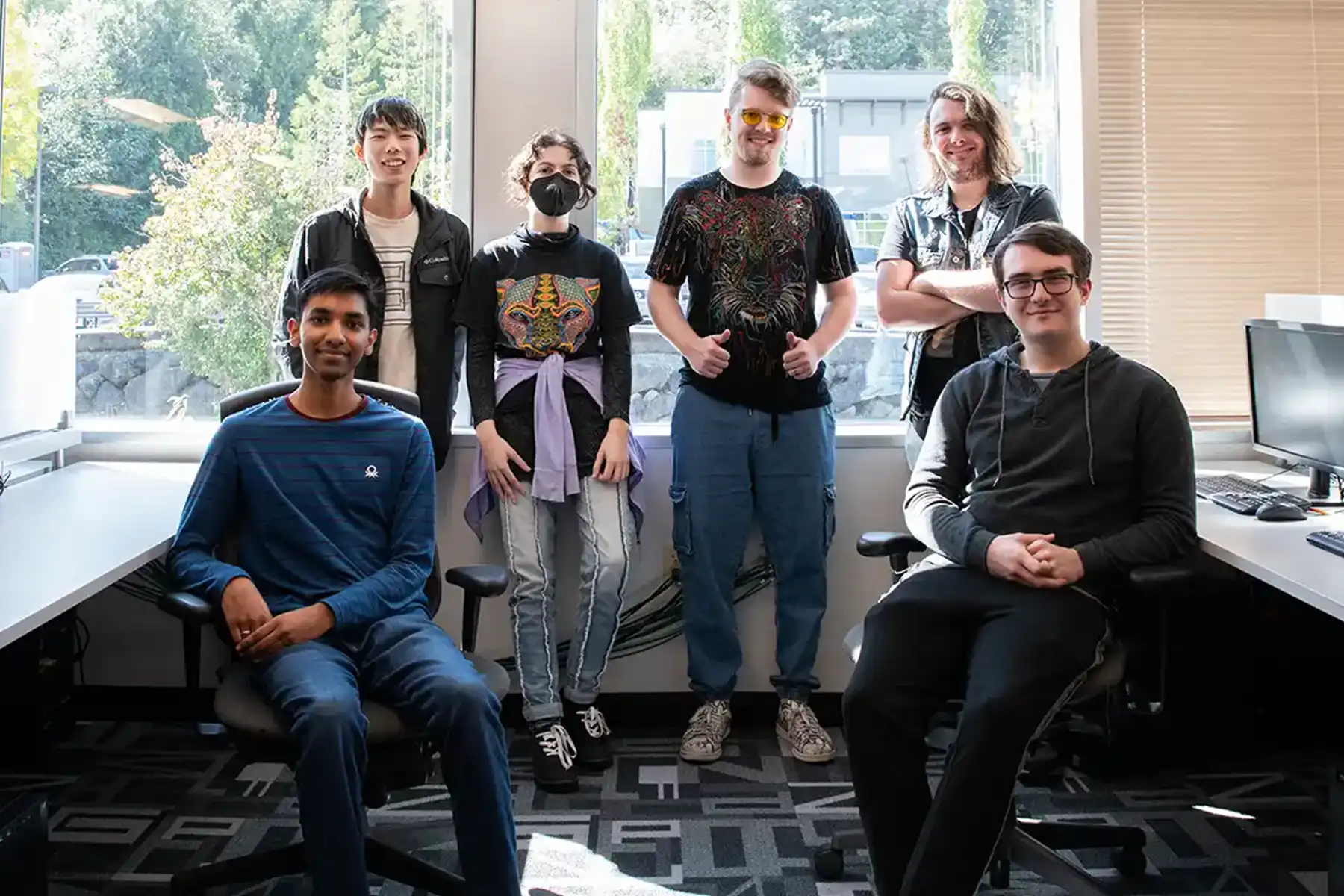 Six members of student team Royal Court pose, half seated, half standing, in the campus production lab.