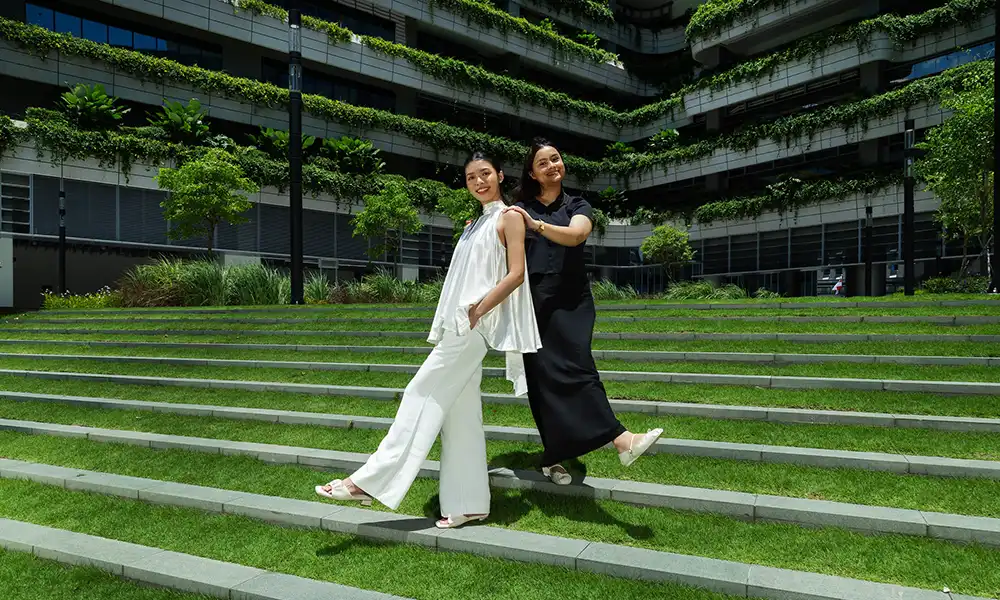 Two students pose on a grass terrace