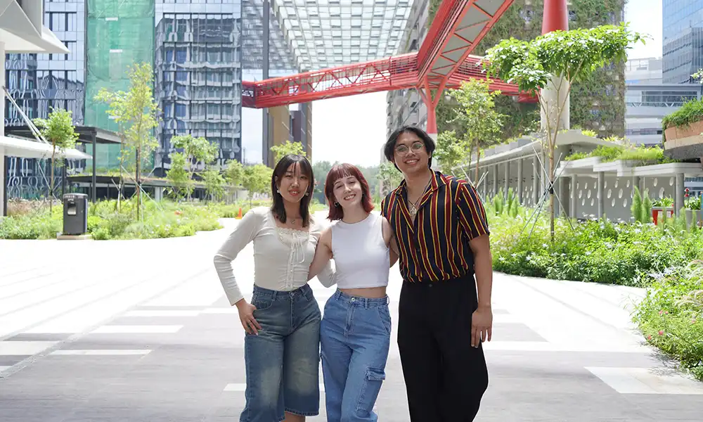 Three student pose outdoors.