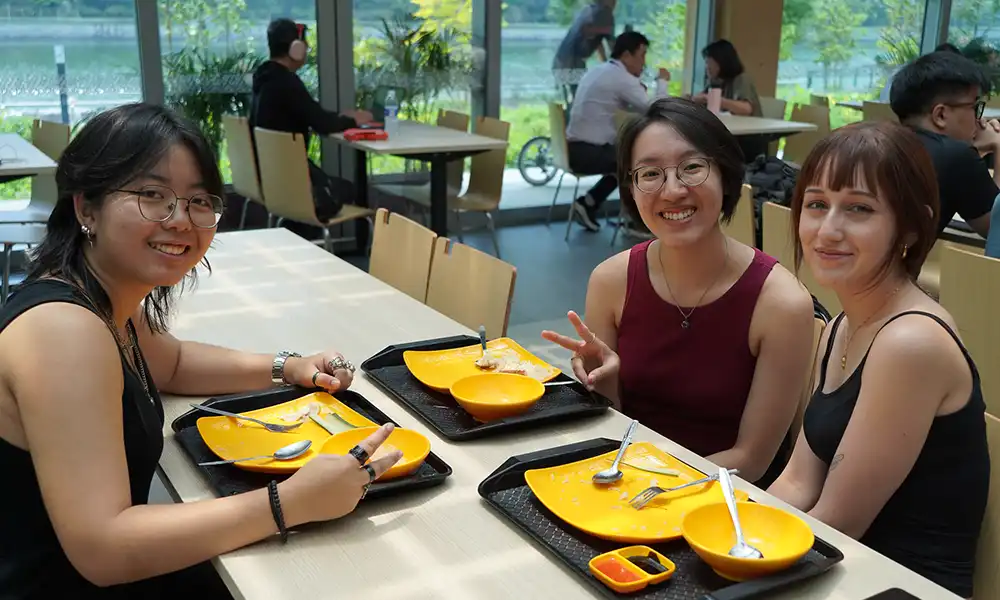 Three students sit in a cafeteria.